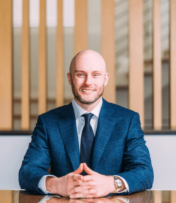 Portrait of Dustin Hahn in a black suit and red tie